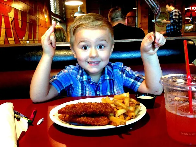 Kid enjoying a meal of chicken tenders and fries