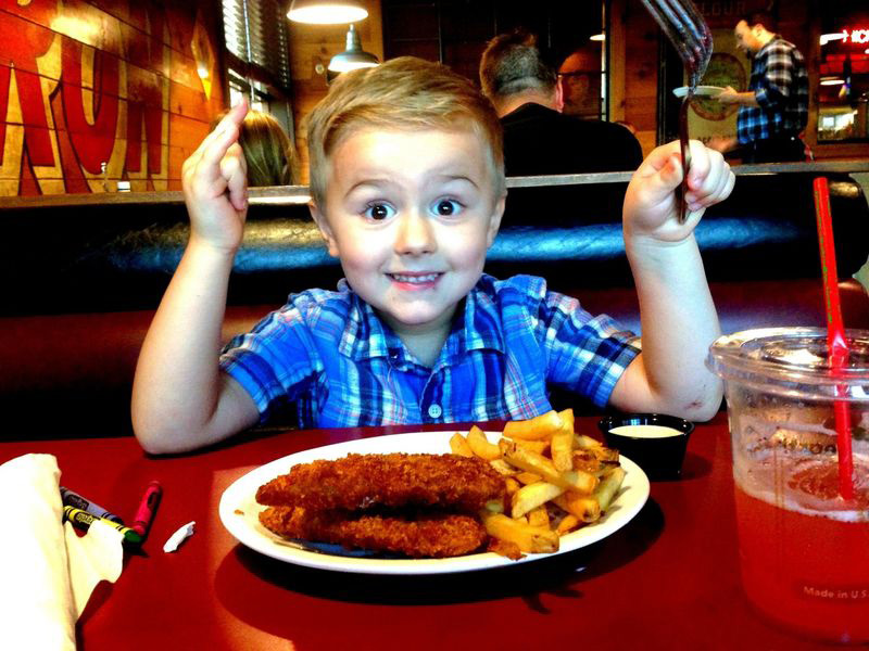 Kid enjoying a meal of chicken tenders and fries